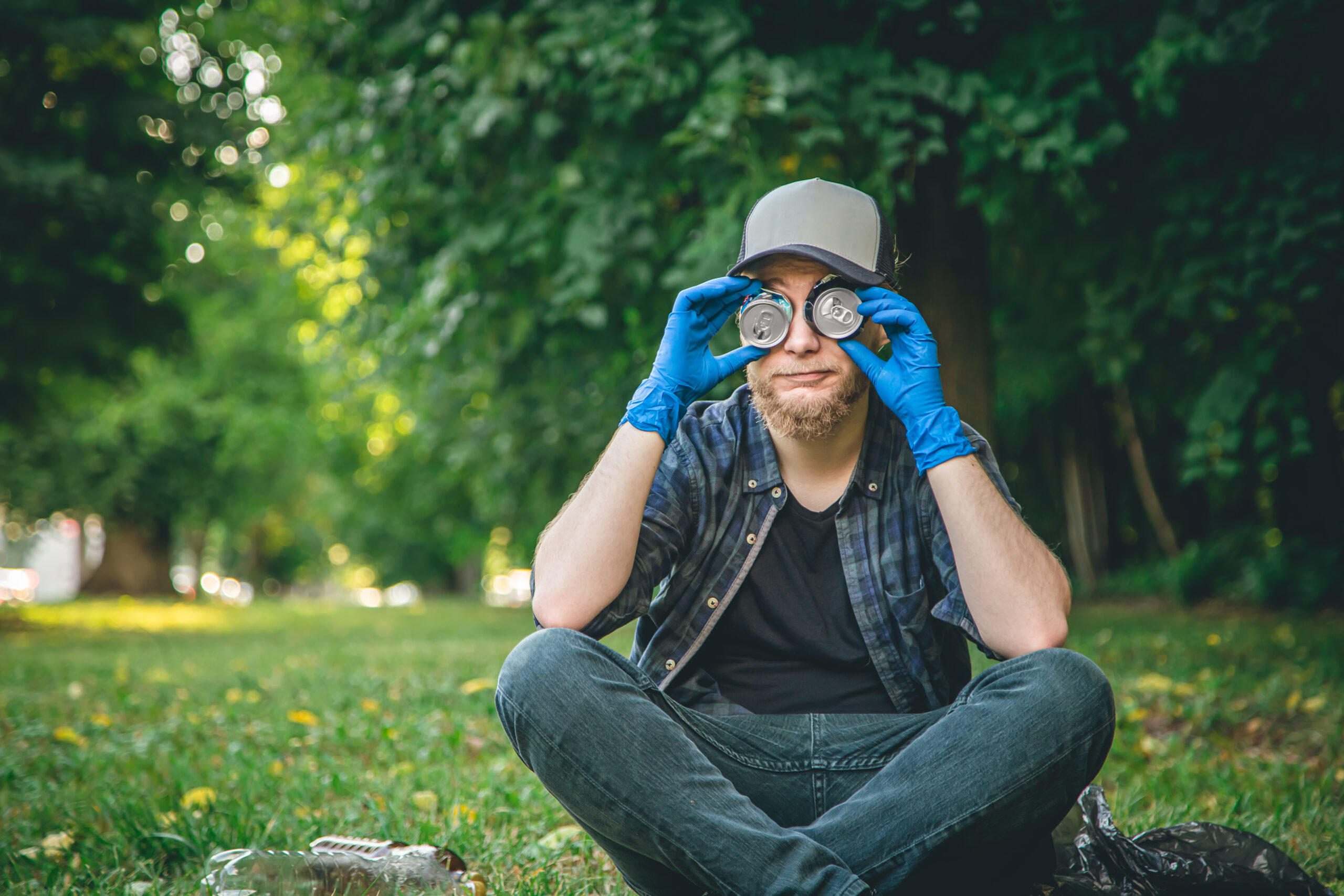 A young man cleaning in the forest, portrait with tin cans.